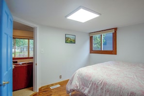 Ein Schlafzimmer mit Bett, Fenster, Tür und Deckenleuchte.