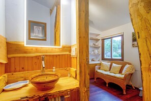 A wooden interior with a wooden sink, a wicker sofa, and a window with a view. - West Okoboji Waterfront Home w/ Private Dock (Milford)