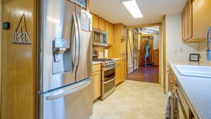 Una cocina moderna con electrodomésticos de acero inoxidable, armarios de madera y un pasillo visible que conduce a otra habitación.