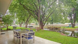 Un patio al aire libre con una mesa y sillas, rodeado de árboles y un pequeño estanque.