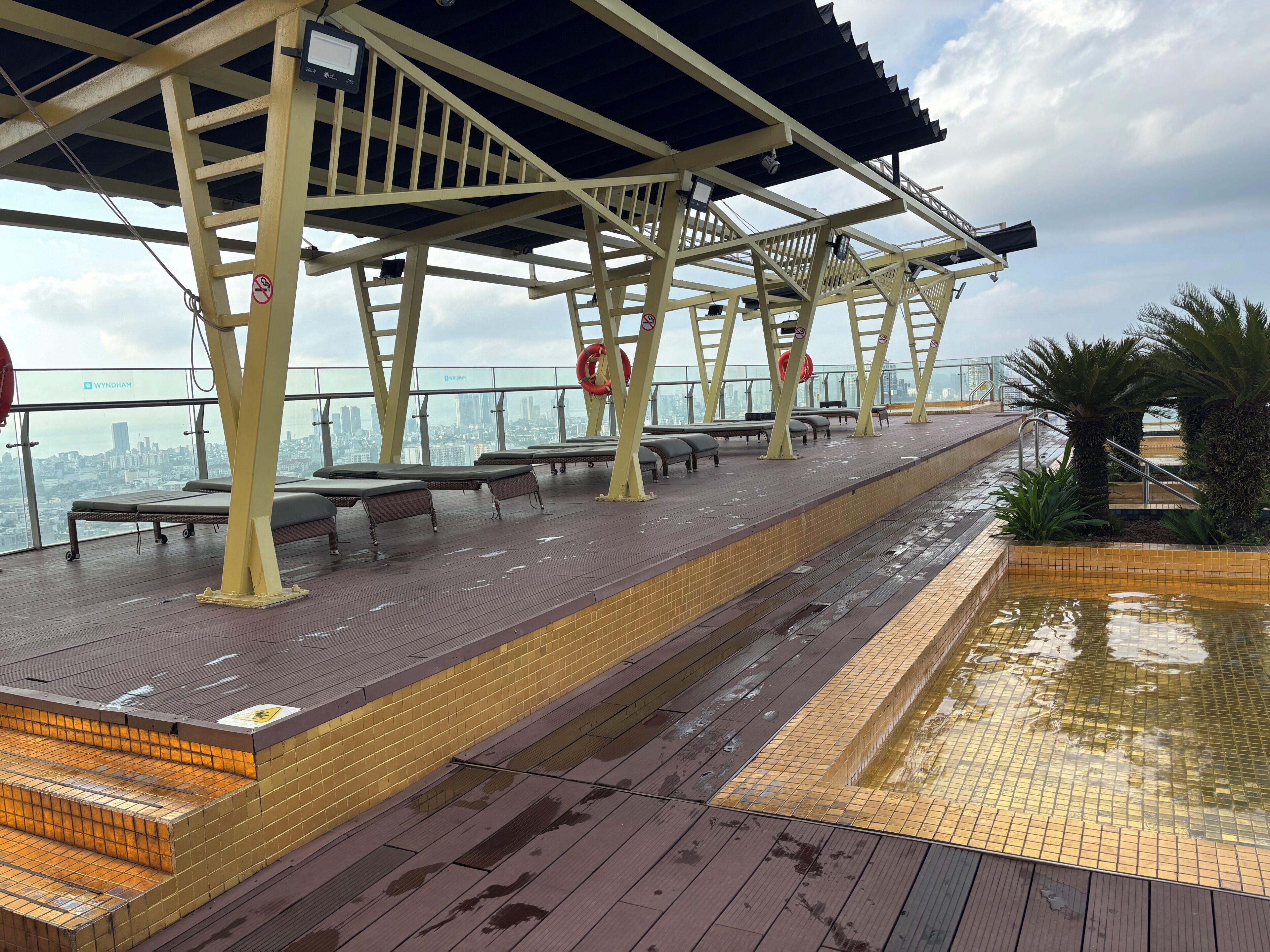 Un espace piscine aménagé sur le toit, avec des chaises longues et une vue sur le panorama urbain.