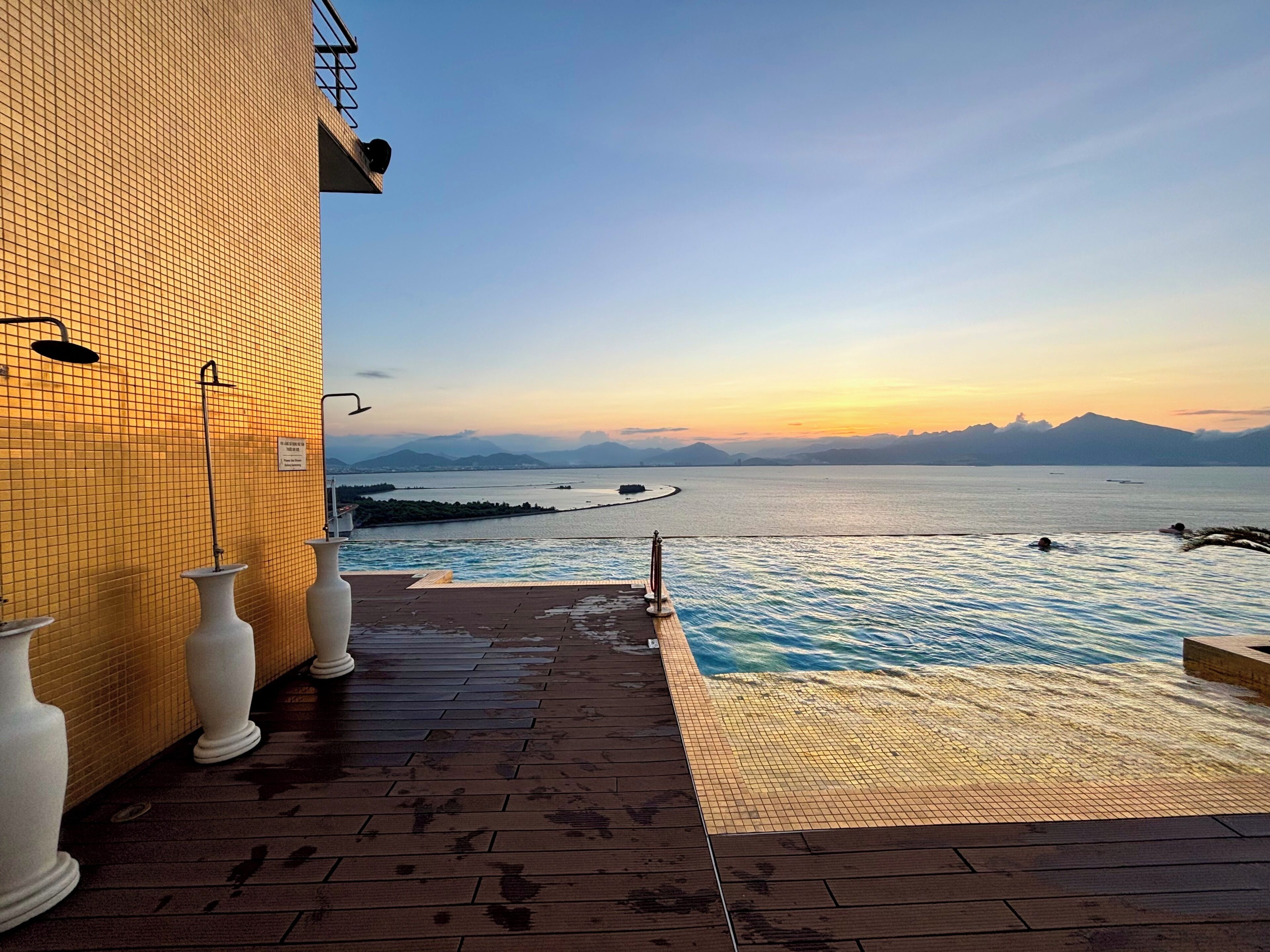 Ein Poolbereich mit Blick auf ein Gewässer und ferne Berge.