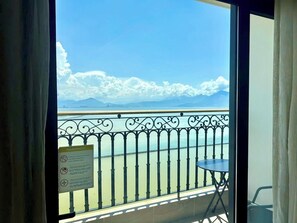 Un balcon avec vue sur la mer et les montagnes, un panneau d’avertissement et une petite table.