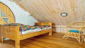 A wooden loft bedroom with a bed, a chair, and a small window.
