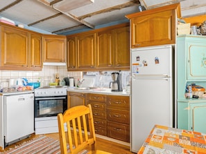 Una cocina compacta con armarios de madera, un refrigerador blanco, una estufa y un lavamanos.