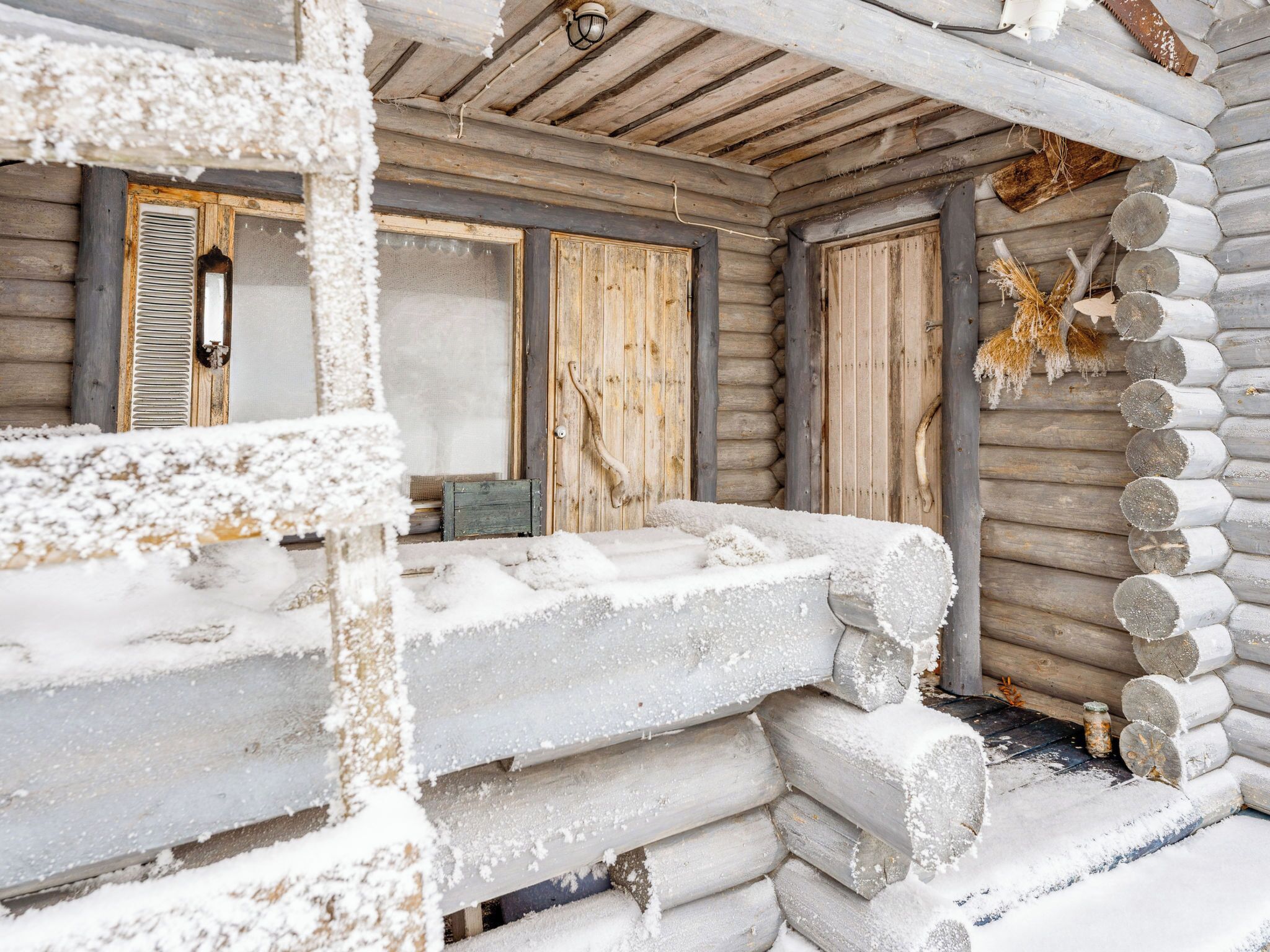 A log cabin with a snow-covered exterior, wooden walls, and a door with a window.