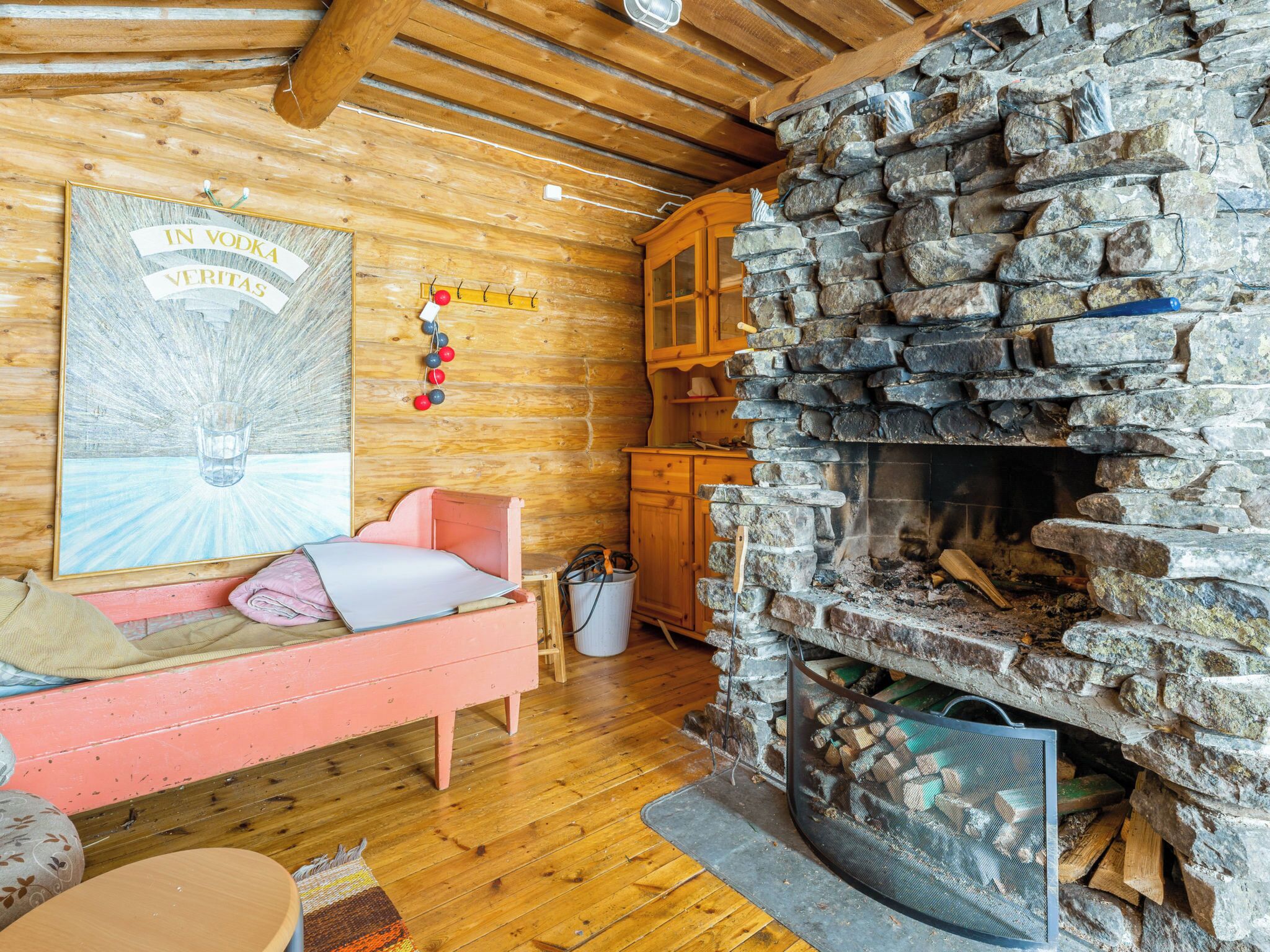Interior acogedor de una cabaña con chimenea de piedra, paredes de madera y una cama con almohadas.