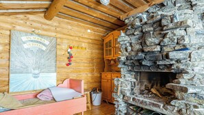 A cozy cabin interior with a stone fireplace, wooden walls, and a bed with pillows.