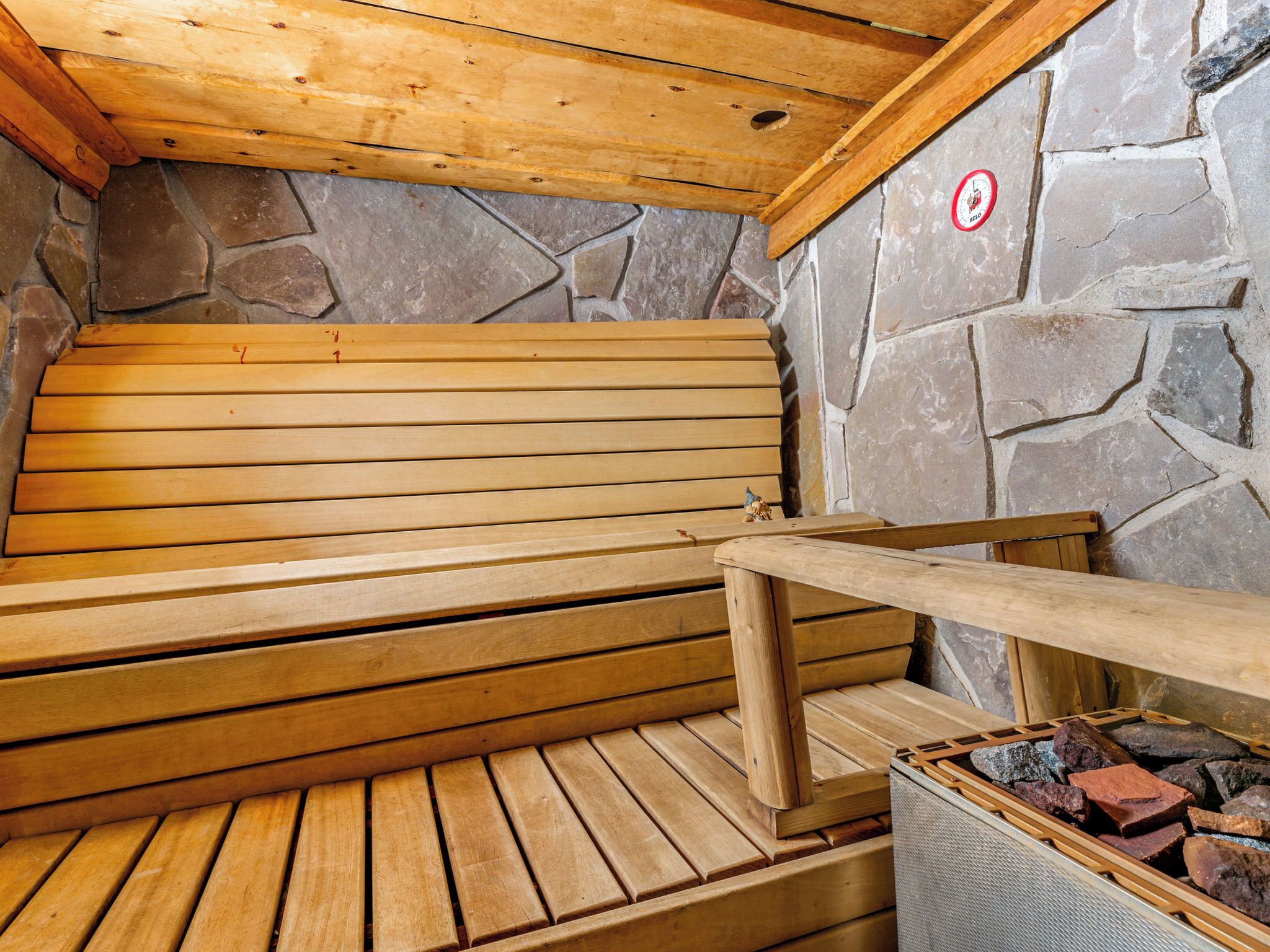 Un sauna avec des bancs en bois et un mur en pierre.