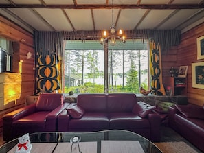 A room with a leather sofa, a glass coffee table, and a chandelier.