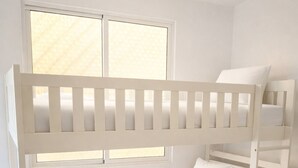 Un lit superposé avec un matelas et des oreillers, une fenêtre avec des stores et un sol carrelé.