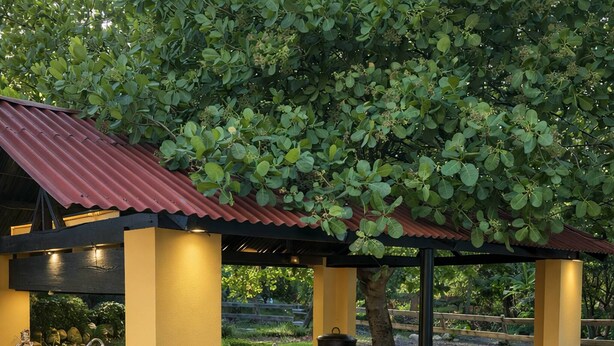 Un espace cuisine extérieur doté d’un four encastré et d’un évier, entouré d’une structure jaune avec un toit rouge.