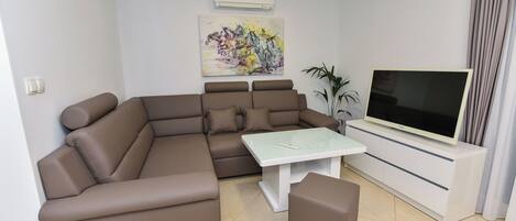 A modern living room with a sectional sofa, a flat-screen TV, and a minimalist design.