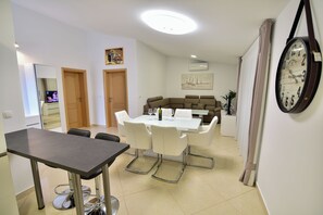 Un área de comedor con una mesa y sillas, un sofá y un reloj en la pared.