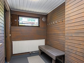 A sauna room with wooden walls, a bench, a window, and a radiator.