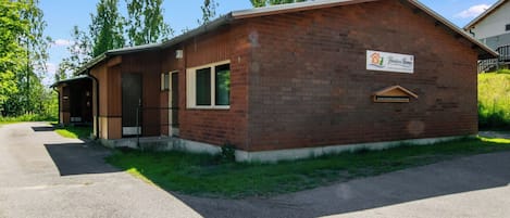 A single-story brick building with a covered porch, a sign indicating it's a Heineken House, and a paved driveway.