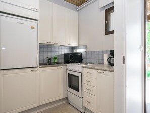 A kitchen with white cabinets, a black microwave, a stove, and a sink.
