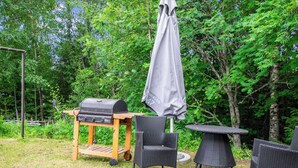 An outdoor patio area with a grill, chairs, and a table.