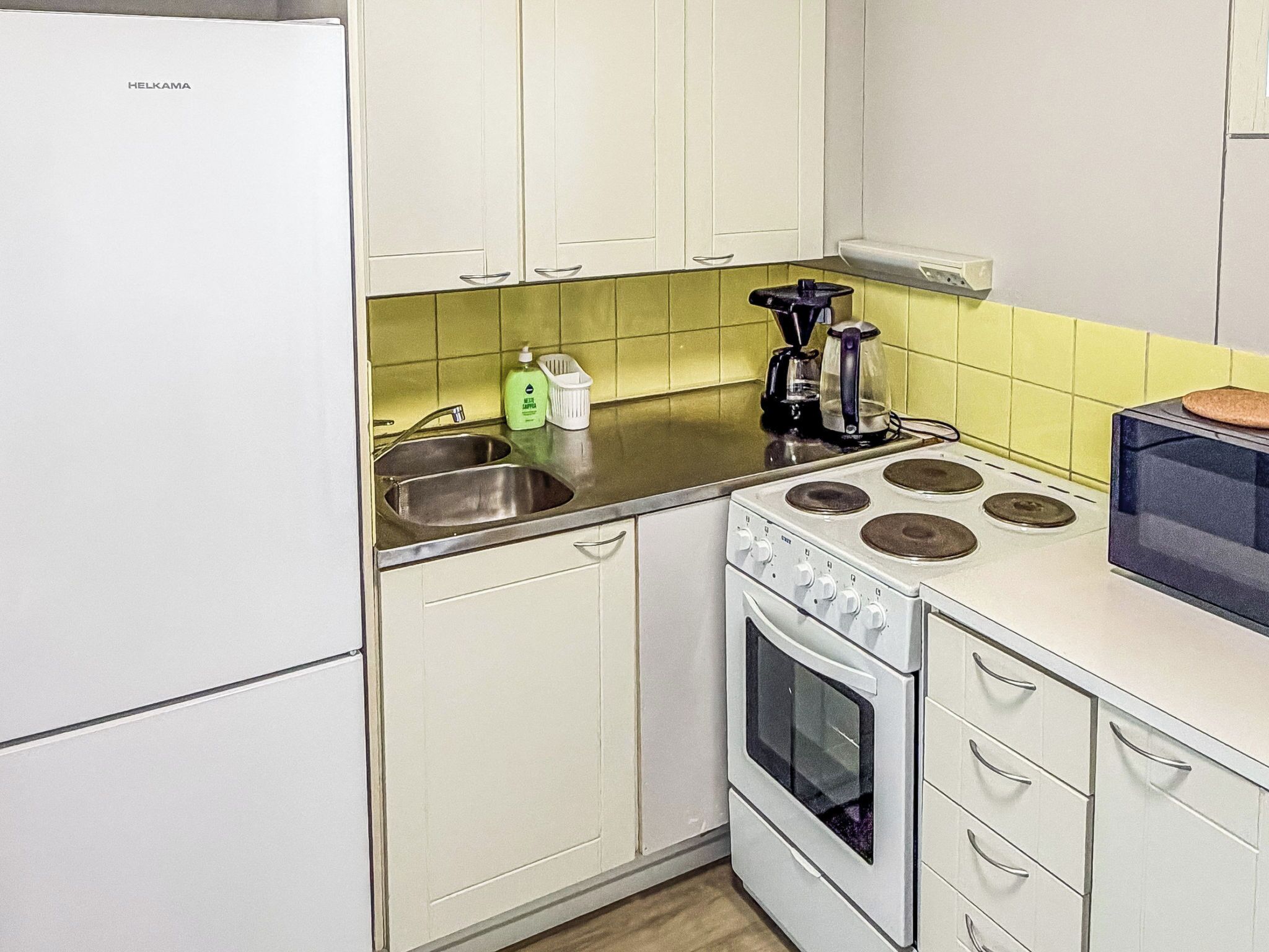 A kitchen with white cabinets, a stove, and a sink.