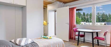 Une chambre moderne comprenant un lit, des tables de chevet, une fenêtre avec vue et un coin repas avec des chaises.