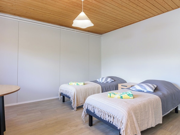 A room with two beds, a small table, and a hanging light fixture.