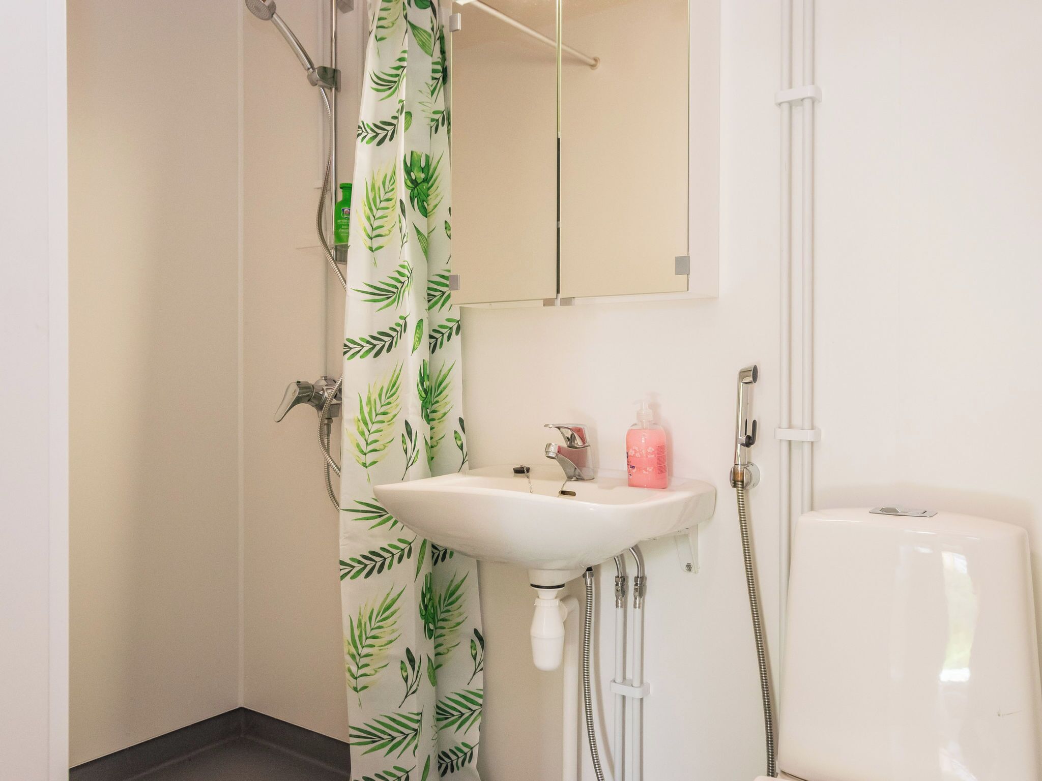 Et badeværelse med bruser, vask og toilet.