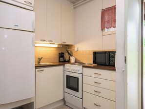 A compact kitchen with a white refrigerator, a stove, a microwave, and a sink.