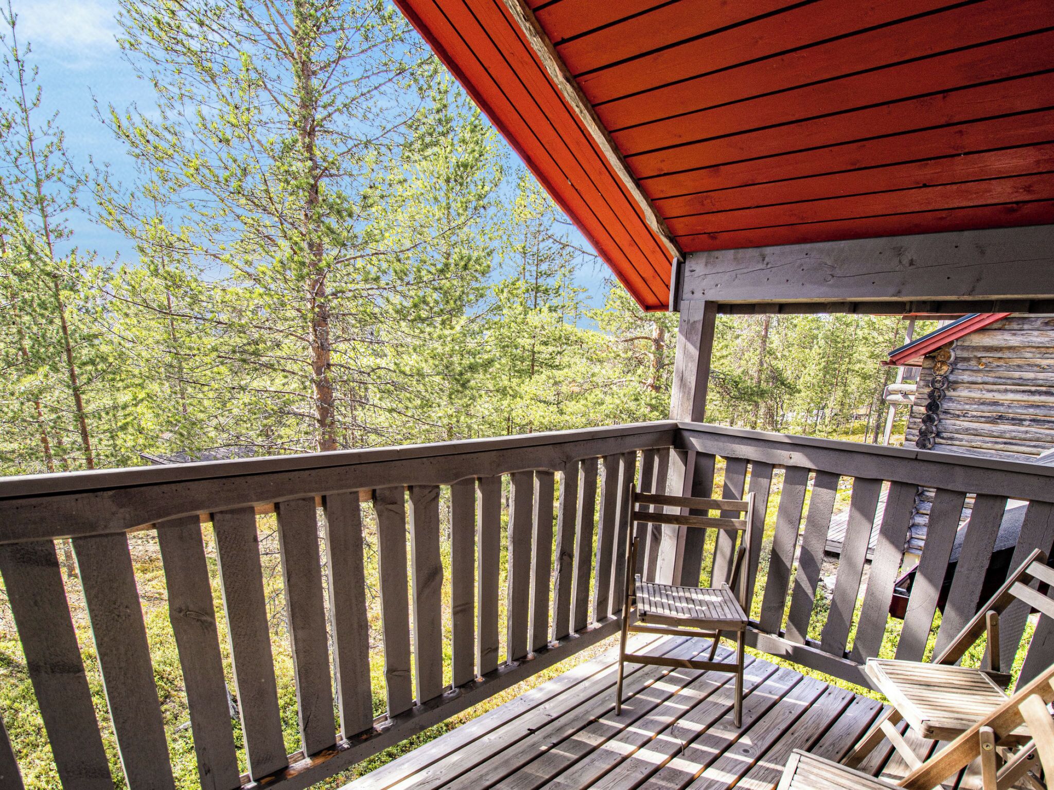 A wooden deck with a bench and a table, overlooking a forested area.