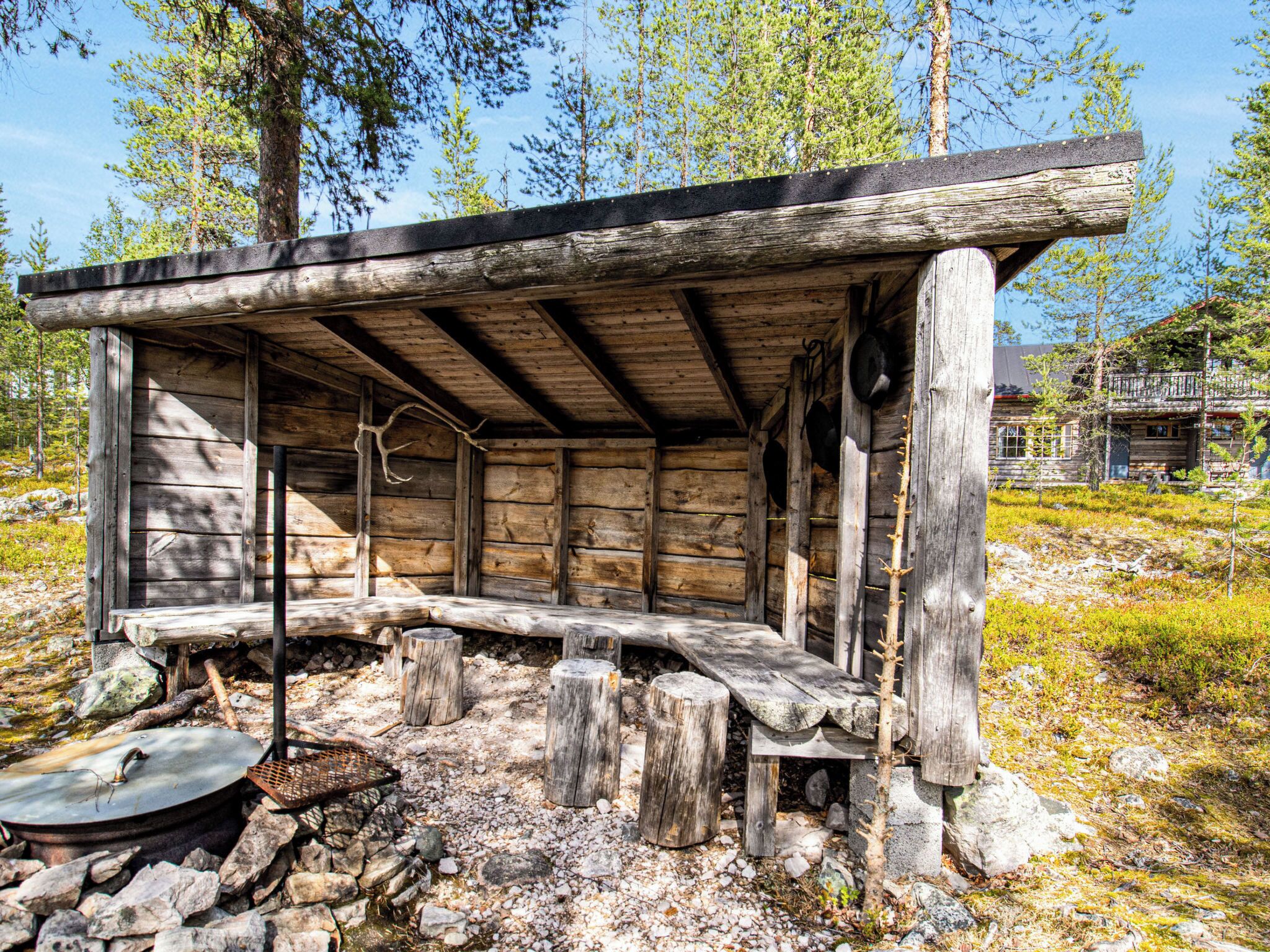A rustic wooden cabin with a bench outside, surrounded by rocks and trees.