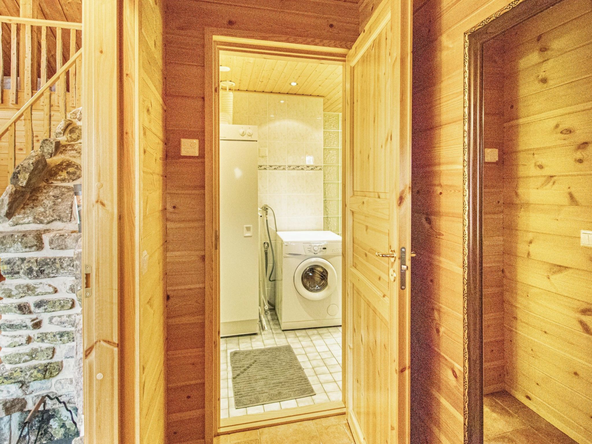 A wooden interior with a stone wall, a washing machine, and a tiled floor.