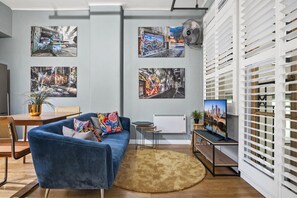 A modern living room with a blue sofa, a coffee table, and a TV on a stand. - Temple Court Suite in Melbourne CBD (Melbourne)