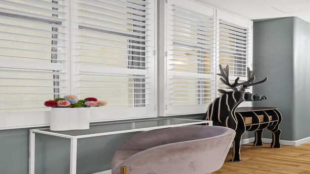 Una habitación de diseño moderno, con una pared gris, suelo de madera, una mesa blanca, una silla morada y una escultura decorativa de cuerno de ciervo.