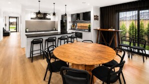 A modern kitchen with a central island, bar stools, and a dining table with chairs. - Spacious 4-Bedroom Family Home in Manor Lakes (Manor Lakes)