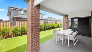 A patio area with a table and chairs, a brick column, and a view of a residential neighborhood. - Spacious 4-Bedroom Family Home in Manor Lakes (Manor Lakes)