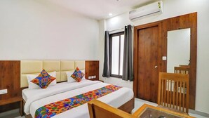 Una habitación de hotel con cama, escritorio, silla y espejo.