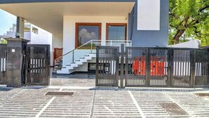 Un edificio moderno con entrada protegida, una escalera y cielo despejado.