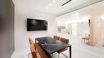 A modern conference room with a large flat-screen TV, a marble table, and leather chairs.