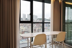 Una habitación moderna con un gran ventanal, dos sillas blancas y una mesa.