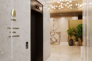 A hotel lobby with a marble floor, a reception desk, and a wall-mounted elevator with a digital display. - HotelTheDeisngers SNU (Seoul)
