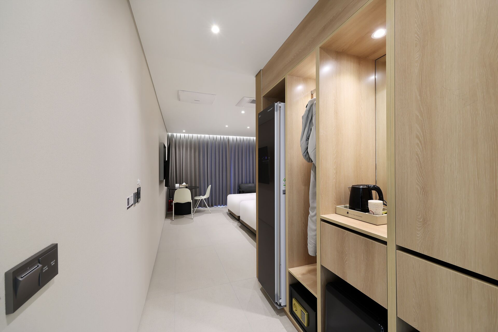 A modern hotel room with a bed, a desk, and a wardrobe.