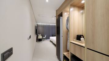 A modern hotel room with a bed, a desk, and a wardrobe.