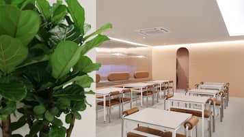 A modern, well-lit room with tables and chairs arranged for dining or meetings.