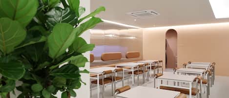 A modern, well-lit room with tables and chairs arranged for dining or meetings.