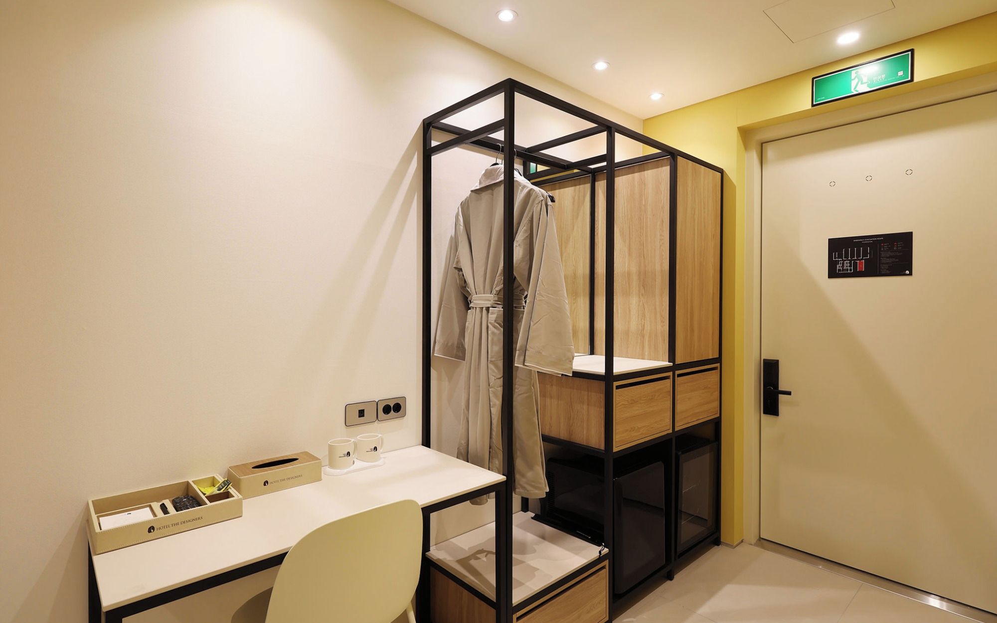 Une chambre d’hôtel équipée d’un bureau, d’une chaise, d’une robe suspendue et d’une armoire avec un miroir.