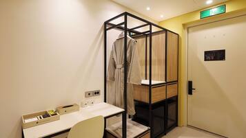 Une chambre d’hôtel équipée d’un bureau, d’une chaise, d’une robe suspendue et d’une armoire avec un miroir.