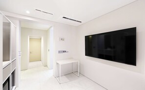 Una habitación de hotel moderna con un televisor de pantalla plana montado en la pared, una consola blanca y un mueble empotrado.