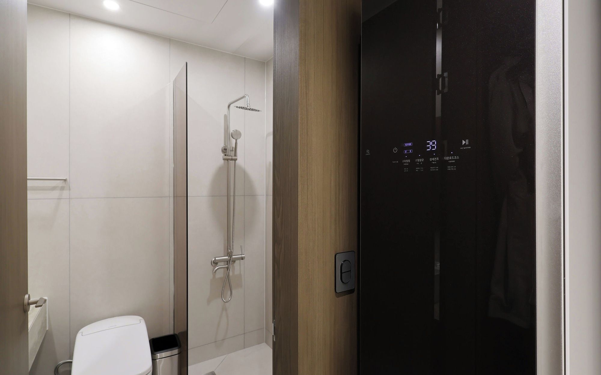 A modern bathroom with a glass shower enclosure, a toilet, and a control panel.