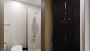A modern bathroom with a glass shower enclosure, a toilet, and a control panel.