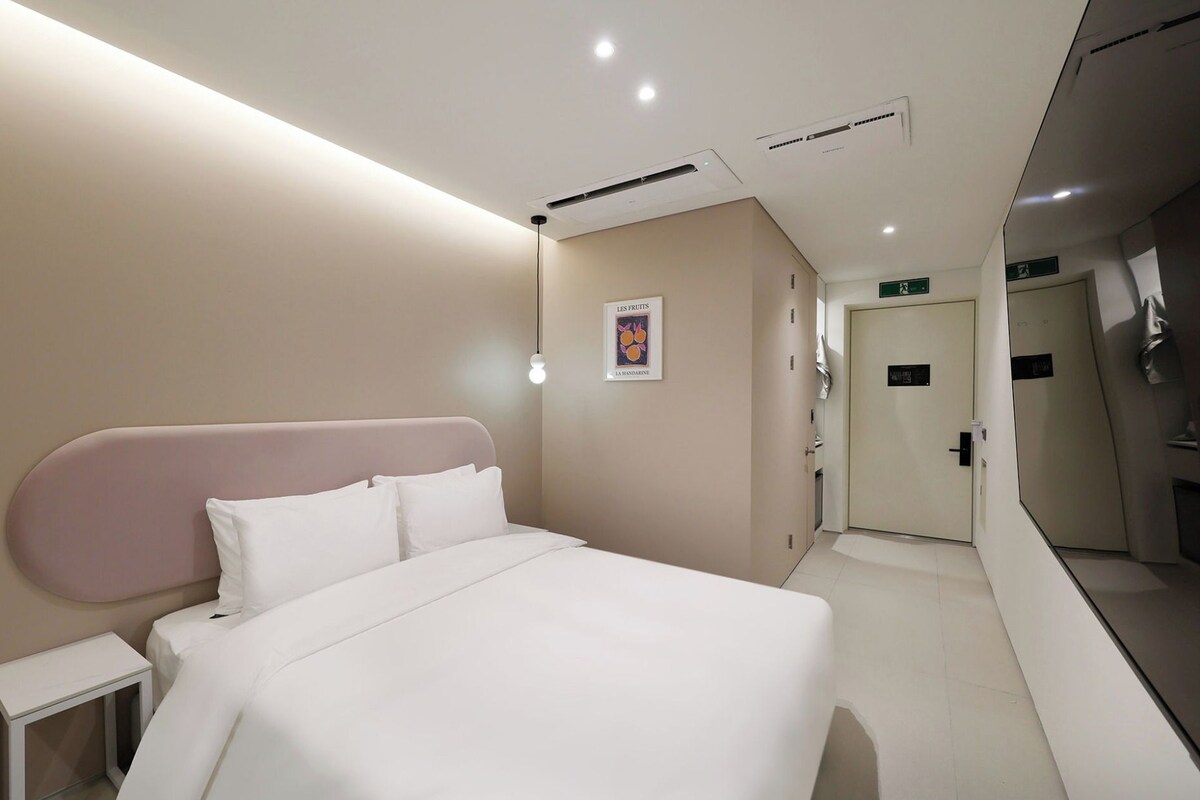 A hotel room with a bed, bedside table, and a poster on the wall.