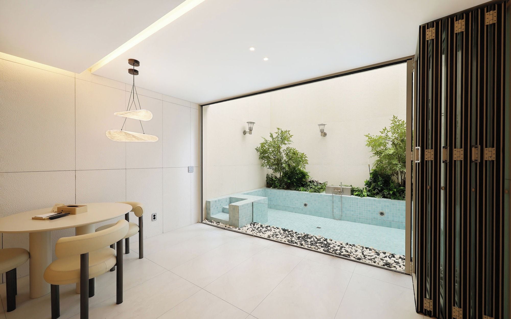 A modern bathroom with a glass-enclosed shower, a round table with chairs, and a minimalist design.